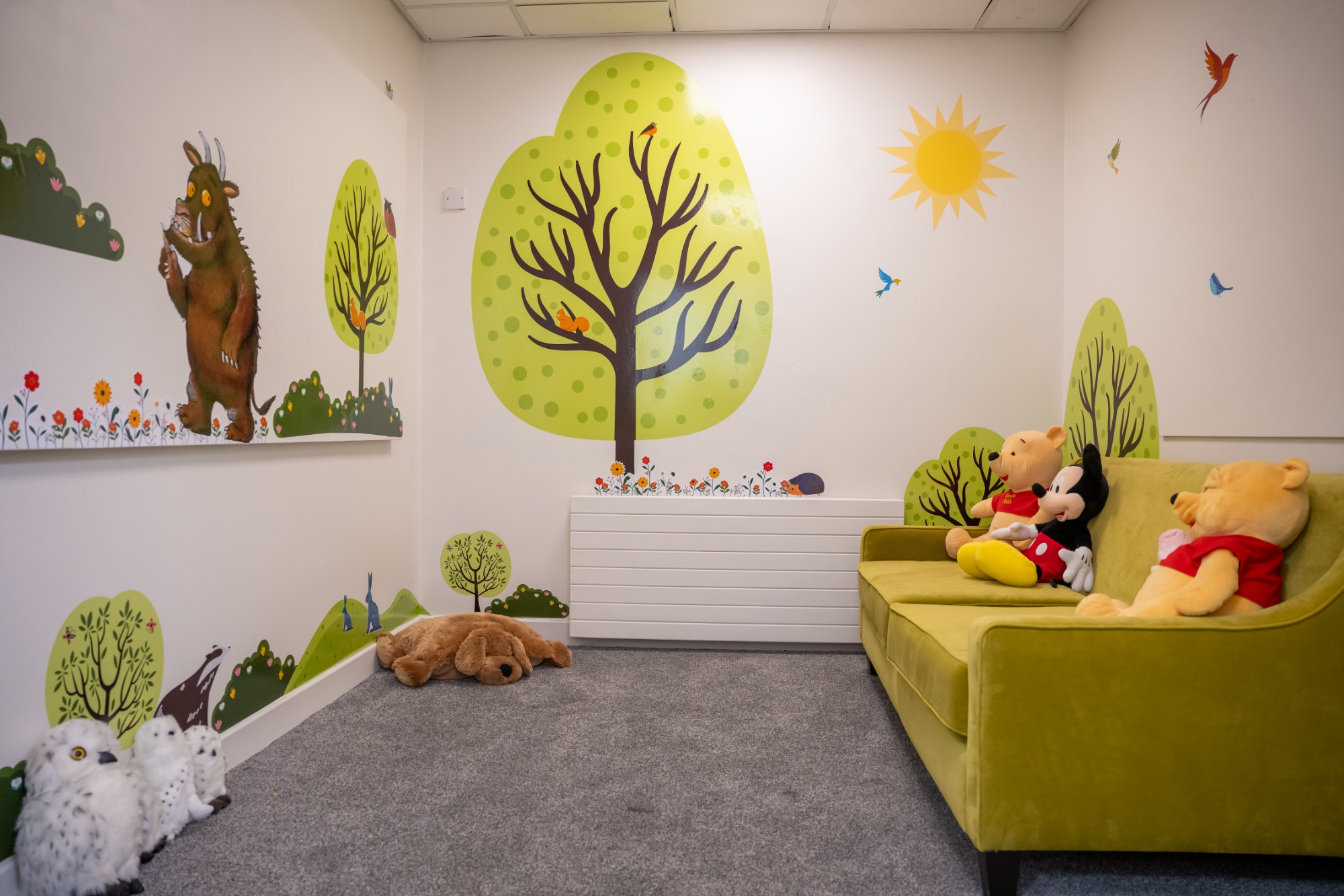 Breakout room with comfy green sofa and soft toys with woodland theme